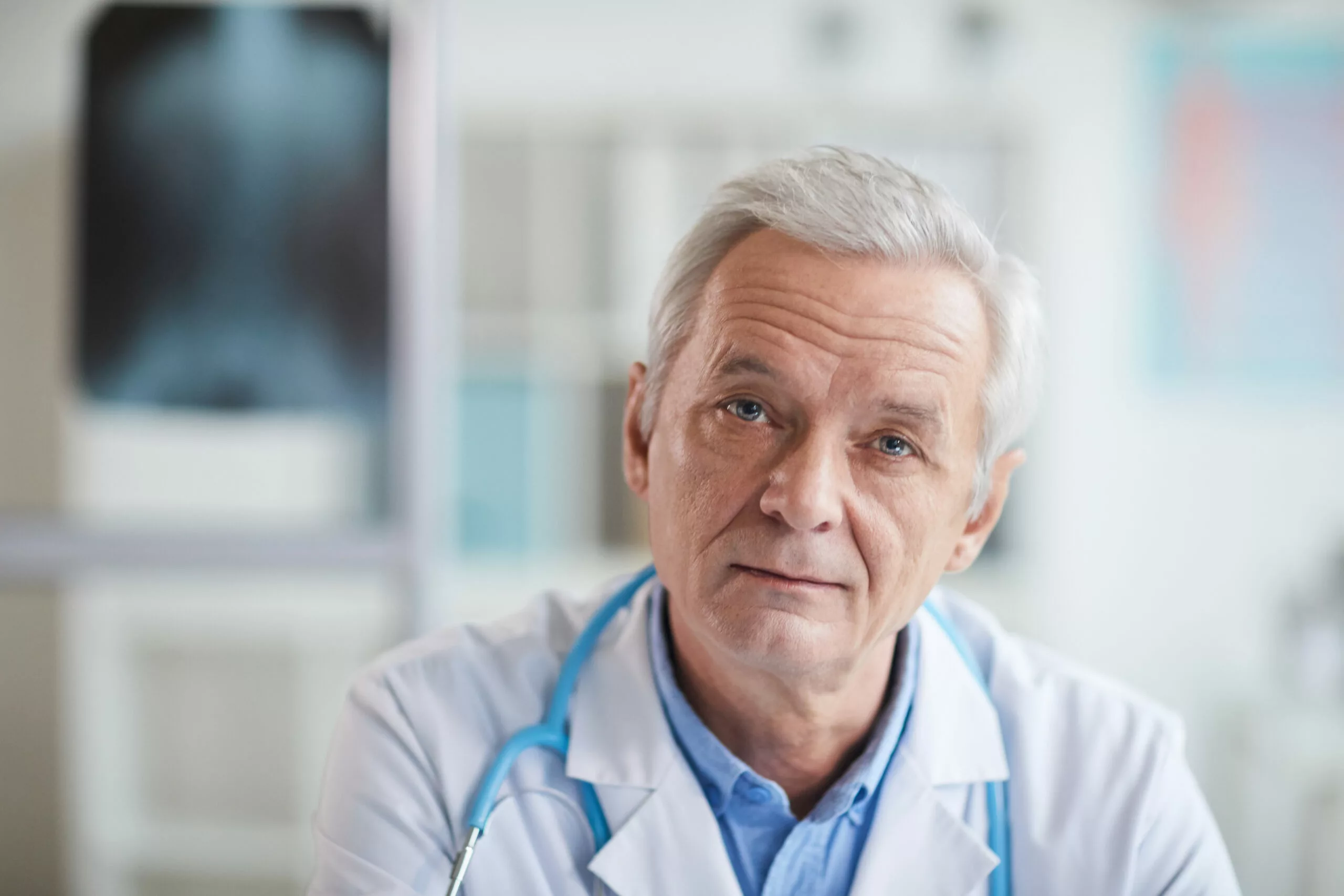 elder medical professional with white hair looking at camera