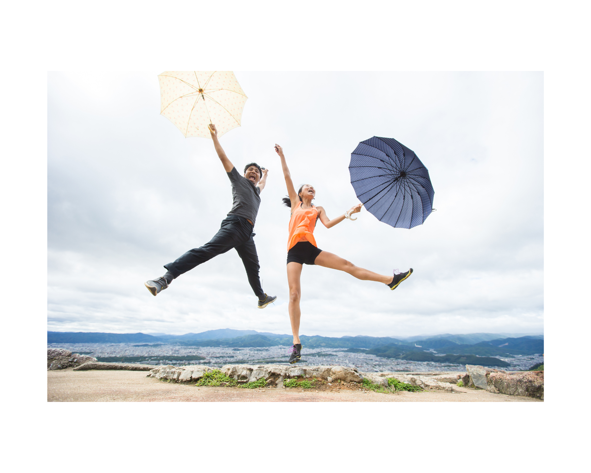 a man and a woman holding an umbrella and jumping joyously